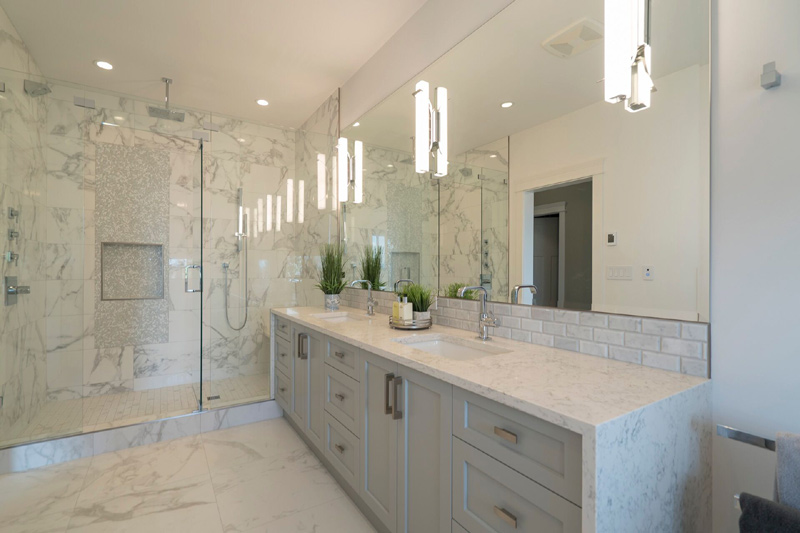 Stunning master ensuite with waterfall countertop on both sides that encases the cabinetry with style. With the added beauty of a custom accent Foilage be bop white glass mosaic from Artistic tile.